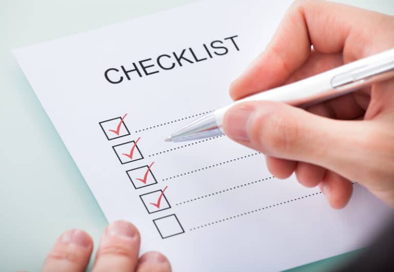 Close-up of a person's hand marking on checklist with pen