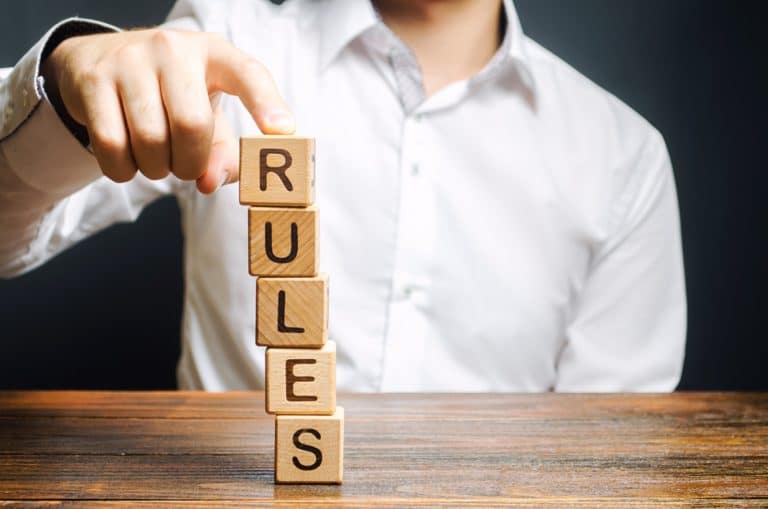 person stacking blocks that spell out RULES